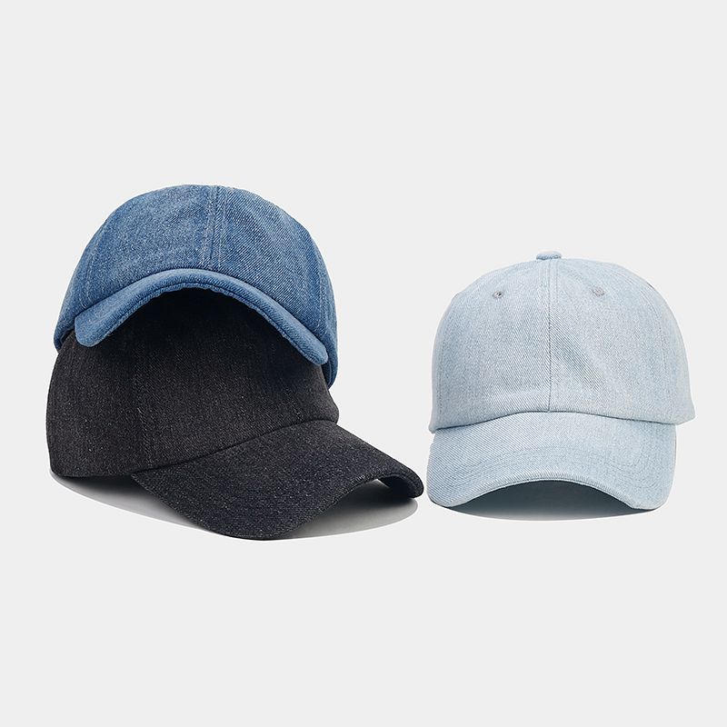 A person showing a denim baseball cap with a logo